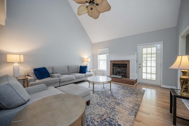 living area featuring ceiling fan, a brick fireplace, wood finished floors, high vaulted ceiling, and baseboards