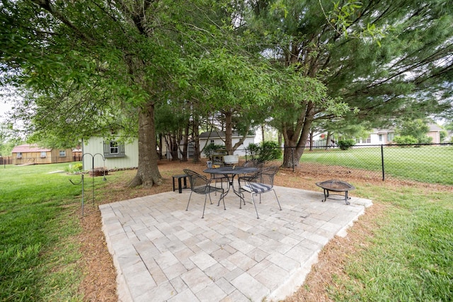 view of patio / terrace featuring a fire pit, fence, and an outbuilding