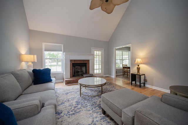 living area featuring a ceiling fan, high vaulted ceiling, plenty of natural light, and baseboards