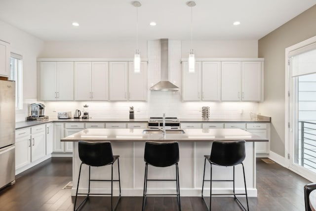 kitchen with wall chimney range hood, backsplash, a sink, and dark wood-style flooring