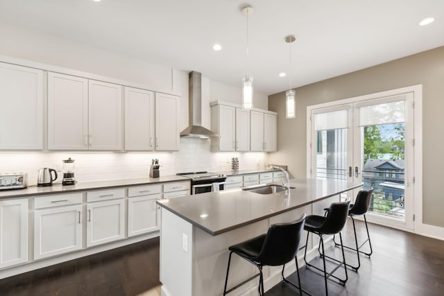 kitchen featuring a sink, tasteful backsplash, dark wood-style flooring, and wall chimney exhaust hood