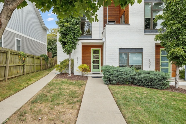 view of front of home with brick siding, a front lawn, and fence