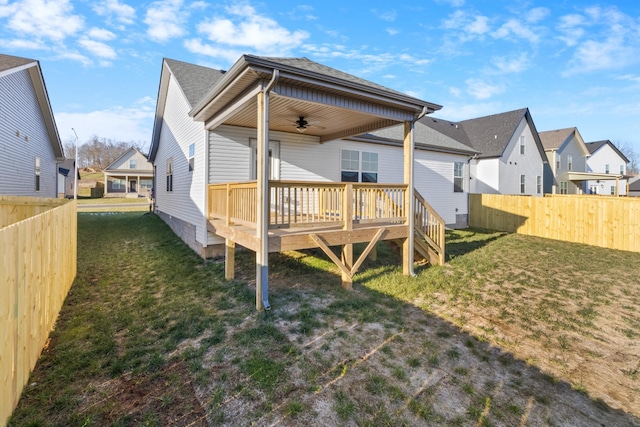 back of property with a lawn, ceiling fan, a wooden deck, and a fenced backyard