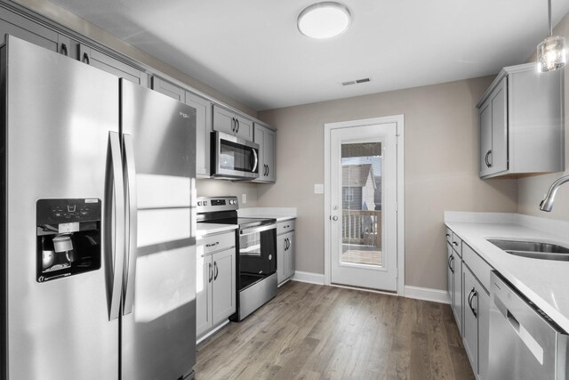 kitchen with gray cabinets, visible vents, appliances with stainless steel finishes, a sink, and light countertops