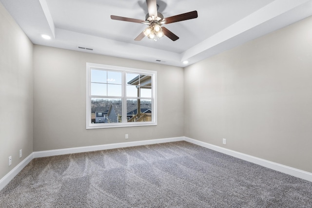 unfurnished room featuring visible vents, carpet floors, baseboards, a raised ceiling, and a ceiling fan