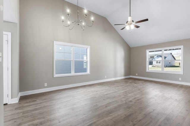 unfurnished living room featuring baseboards, ceiling fan with notable chandelier, wood finished floors, and high vaulted ceiling