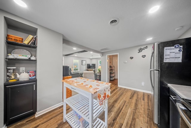 kitchen with baseboards, freestanding refrigerator, wood finished floors, and visible vents