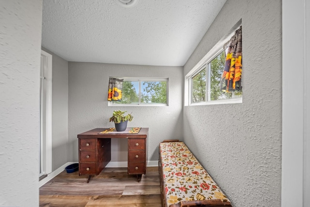 living area with baseboards, a textured ceiling, a textured wall, and wood finished floors