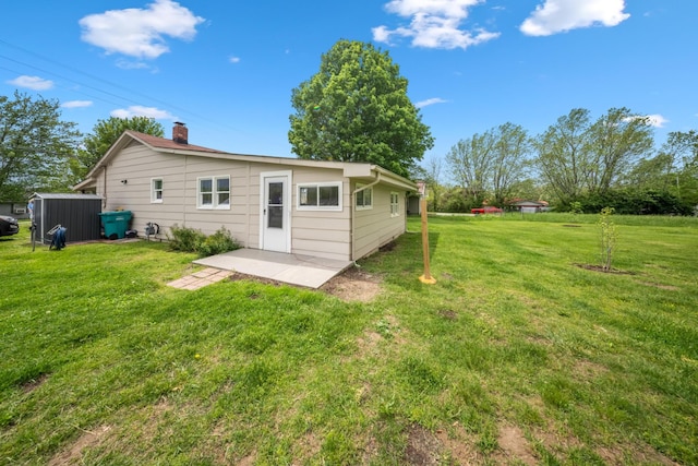 rear view of house featuring a yard, a chimney, and a patio area