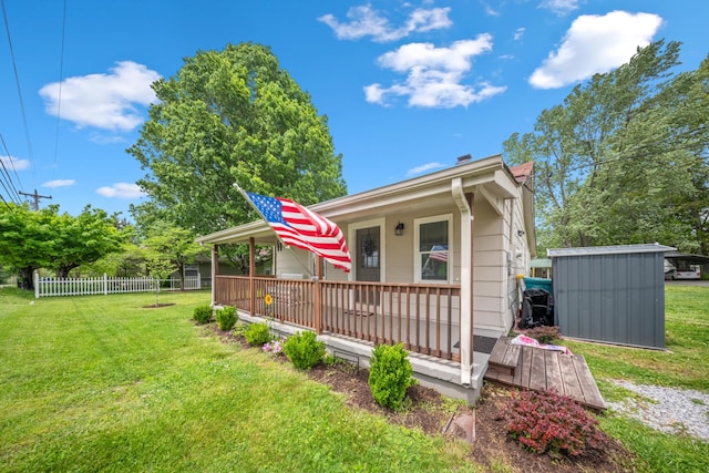view of front of home with a storage shed, fence, an outbuilding, and a front lawn