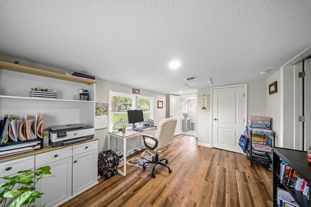 office space featuring a textured ceiling, recessed lighting, wood finished floors, and visible vents