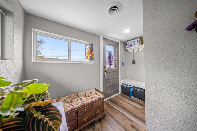 interior space featuring a textured wall, a textured ceiling, dark wood finished floors, recessed lighting, and visible vents
