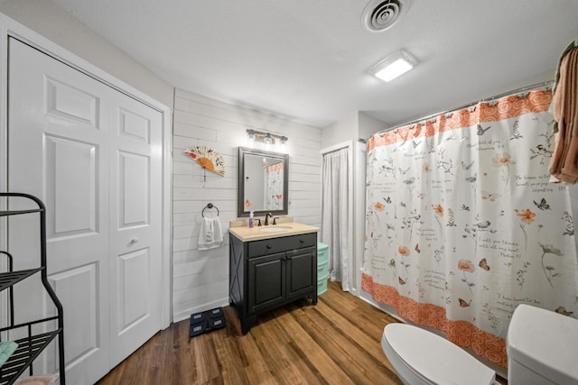 bathroom featuring a shower with shower curtain, toilet, visible vents, and wood finished floors
