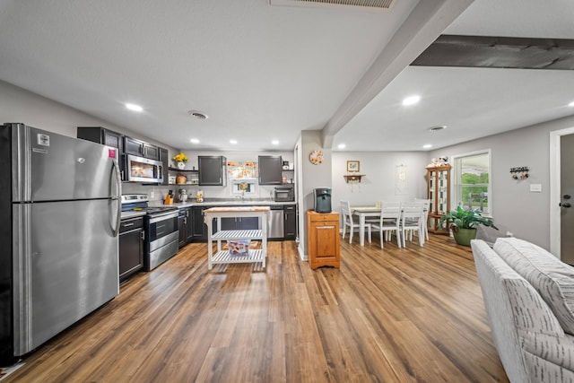 kitchen with light countertops, open shelves, wood finished floors, and stainless steel appliances