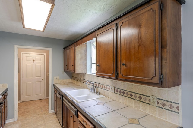 kitchen with stainless steel dishwasher, baseboards, tile counters, tasteful backsplash, and a sink
