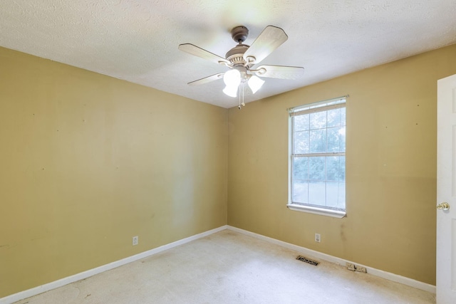 spare room featuring baseboards, visible vents, light carpet, and ceiling fan