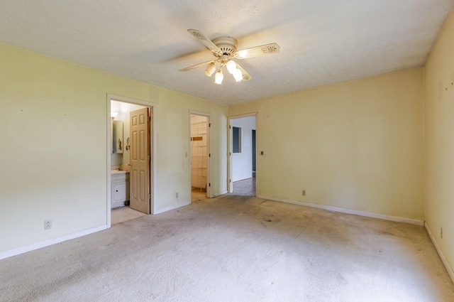 unfurnished bedroom with connected bathroom, baseboards, light colored carpet, and ceiling fan