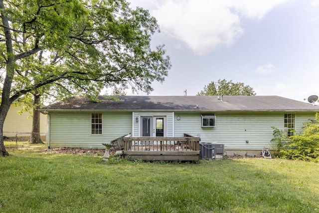 rear view of property with a lawn, fence, central AC unit, and a deck