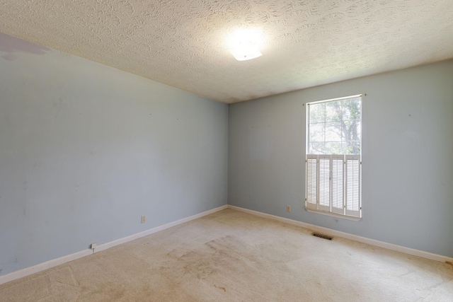empty room with visible vents, a textured ceiling, carpet, and baseboards