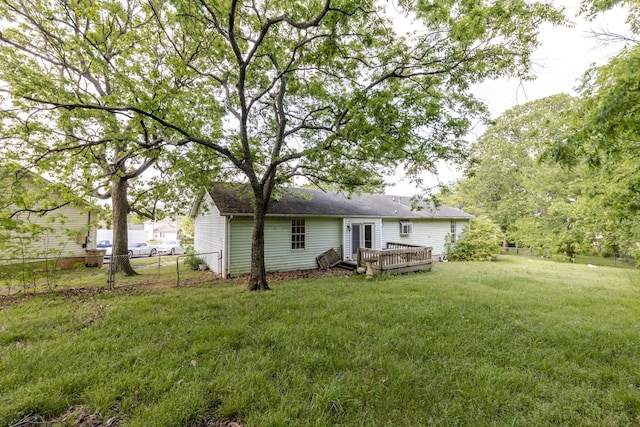 rear view of house with a lawn, roof with shingles, fence, and a deck