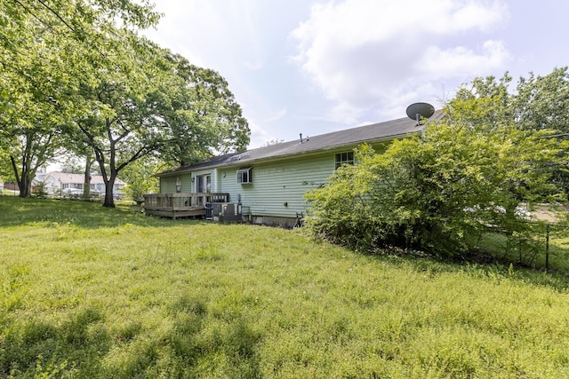 back of property featuring a lawn, fence, and a deck