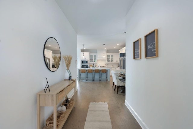 hallway featuring baseboards, recessed lighting, and wood finished floors