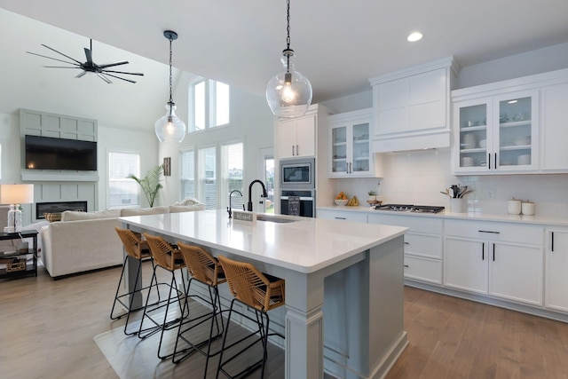 kitchen featuring a sink, a kitchen breakfast bar, stainless steel appliances, decorative backsplash, and a center island with sink