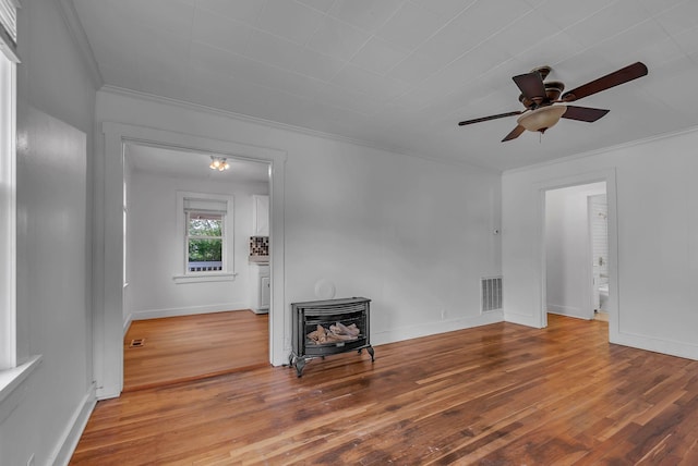 living room featuring crown molding, ceiling fan, a wood stove, and hardwood / wood-style floors