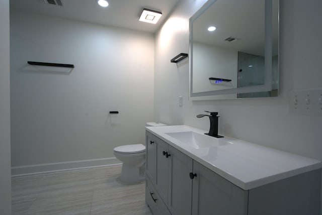 bathroom with vanity, recessed lighting, baseboards, and toilet