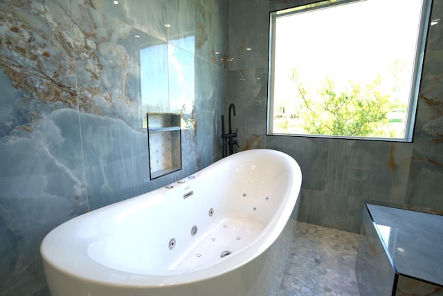 full bathroom featuring a soaking tub and tile walls