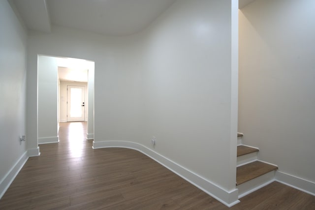 hallway featuring baseboards, dark wood finished floors, and stairs