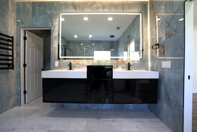 full bathroom featuring double vanity, marble finish floor, and tile walls