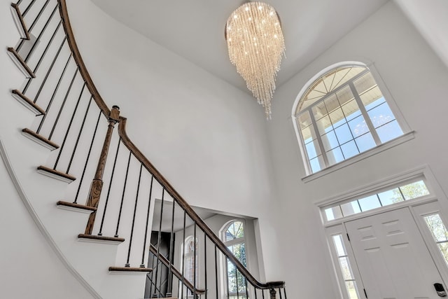 foyer with an inviting chandelier, stairway, and a towering ceiling