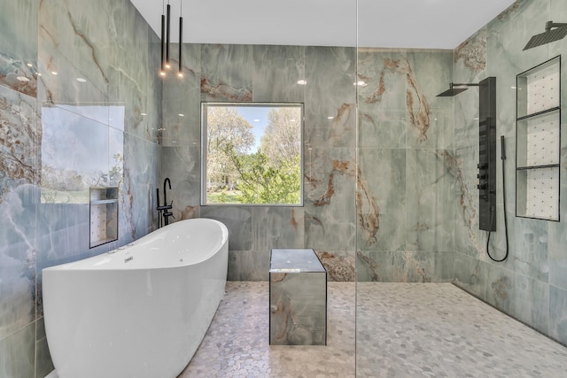 bathroom featuring walk in shower, a freestanding bath, and tile walls