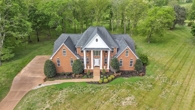 greek revival inspired property featuring a shingled roof, concrete driveway, and brick siding