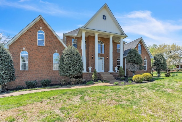 greek revival house featuring a front lawn and brick siding