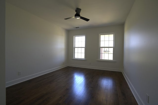 empty room featuring baseboards, a ceiling fan, dark wood finished floors, and visible vents