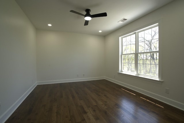 unfurnished room with baseboards, visible vents, and dark wood-style floors