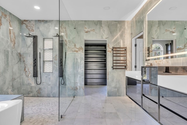 full bath with tile walls, walk in shower, a soaking tub, and vanity