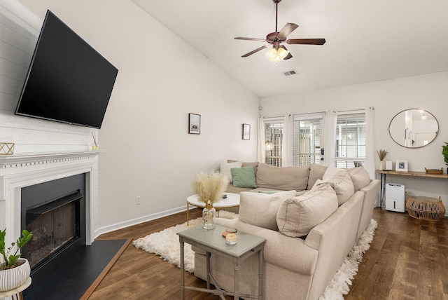 living area with ceiling fan, a fireplace with raised hearth, baseboards, wood finished floors, and visible vents