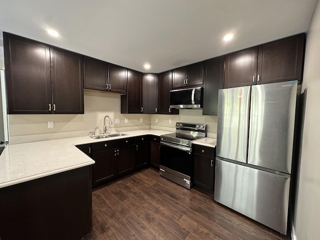 kitchen with dark brown cabinets, a sink, light countertops, stainless steel appliances, and dark wood-type flooring