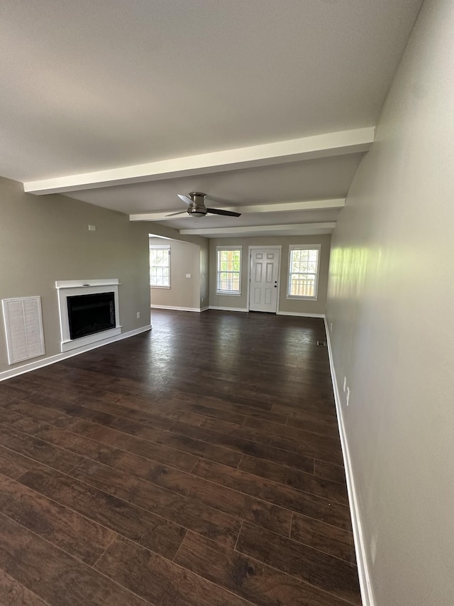 unfurnished living room featuring dark wood-style flooring, ceiling fan, baseboards, beamed ceiling, and visible vents