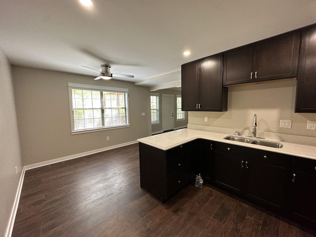 kitchen with a sink, dark wood finished floors, a peninsula, and light countertops