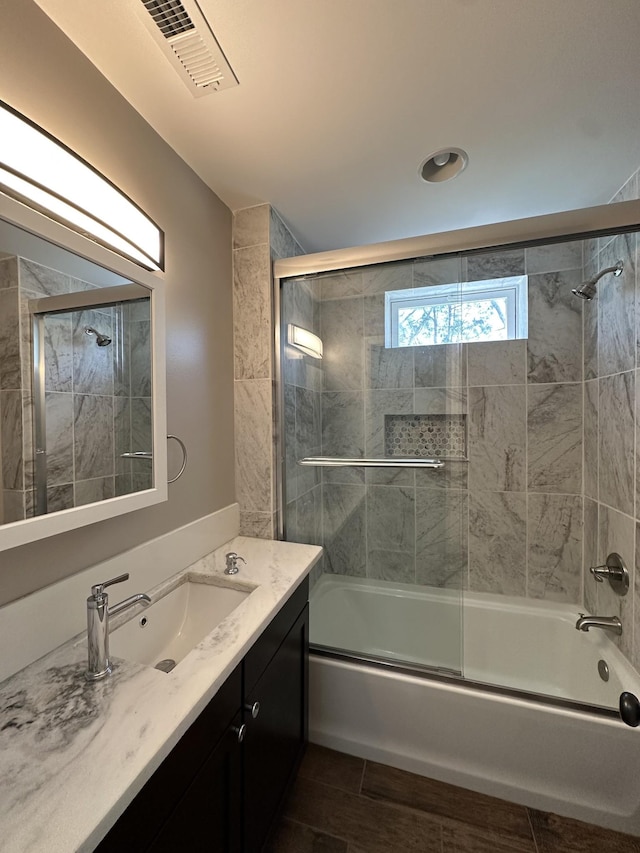 bathroom with vanity, enclosed tub / shower combo, wood finished floors, and visible vents