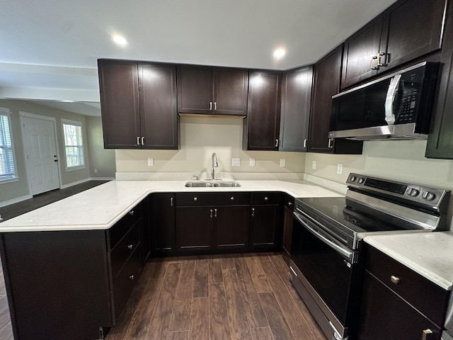 kitchen featuring a sink, light countertops, dark wood finished floors, stainless steel appliances, and a peninsula
