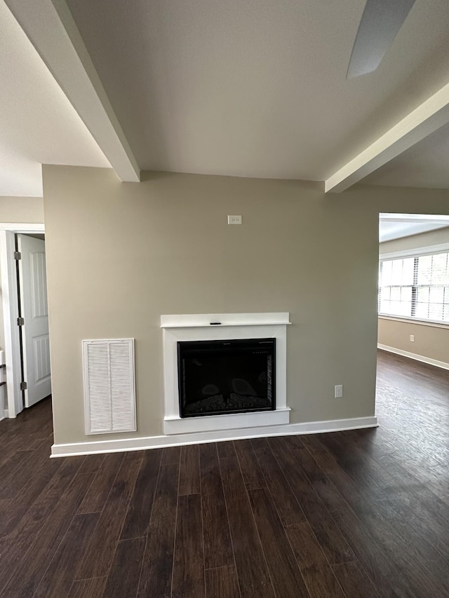 unfurnished living room with visible vents, wood finished floors, beamed ceiling, baseboards, and a fireplace with raised hearth