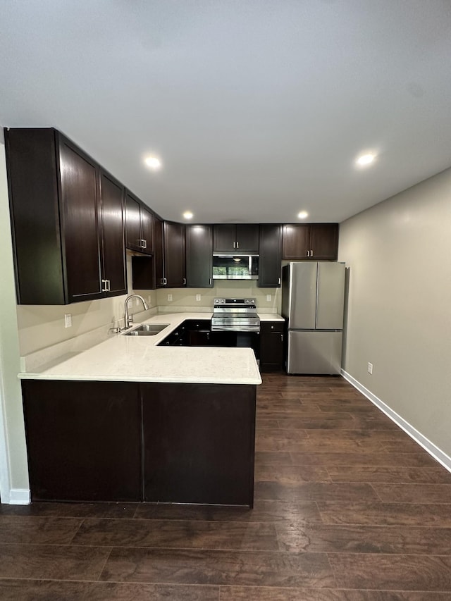 kitchen featuring a peninsula, dark brown cabinets, light countertops, a sink, and appliances with stainless steel finishes
