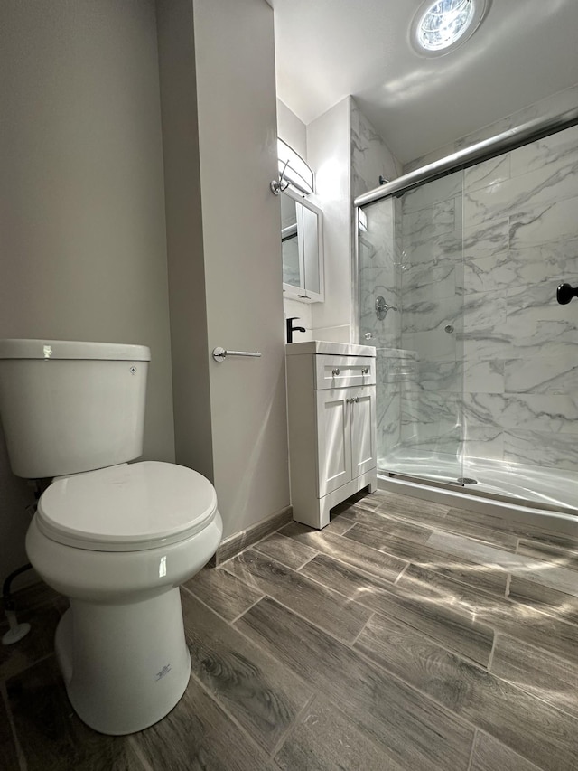 full bathroom with wood finished floors, toilet, a marble finish shower, and vanity