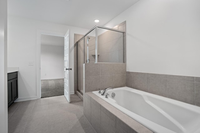 bathroom featuring tile patterned flooring, vanity, baseboards, a garden tub, and a stall shower