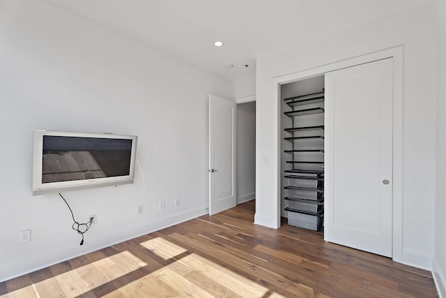 unfurnished bedroom with baseboards, recessed lighting, wood finished floors, and a closet
